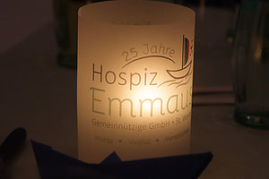 Leuchtende Kerze mit der Aufschrift '25 Jahre Hospiz Emmaus Gemeinnützige GmbH St. Wendel' und einem Segelboot-Symbol