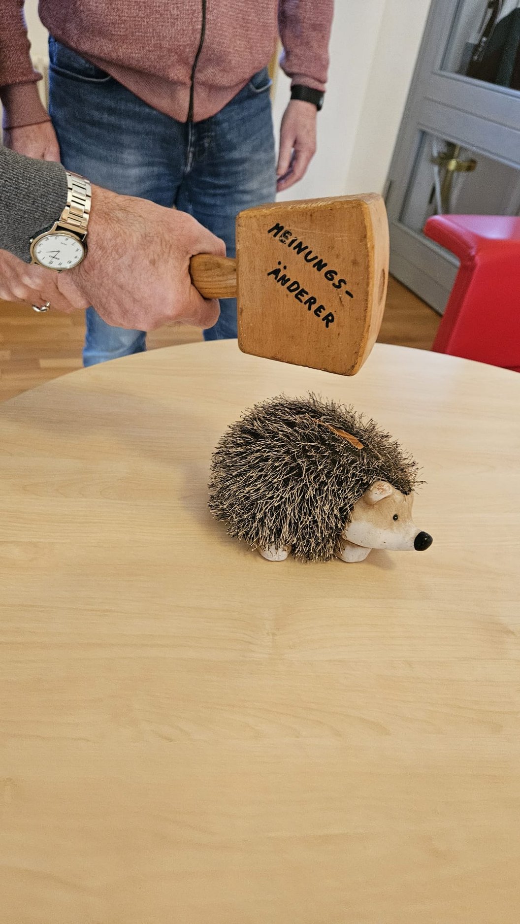 Niedlicher Igel und Holzhammer mit der Aufschrift 'Meinungsänderer' auf einem Tisch.